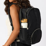 Woman carrying black travel backpack with water bottle in side pocket. #black