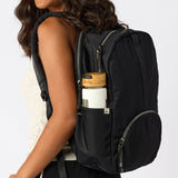Woman carrying black travel backpack with water bottle in side pocket. #black
