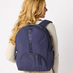 Woman holding indigo travel backpack side view. #indigo