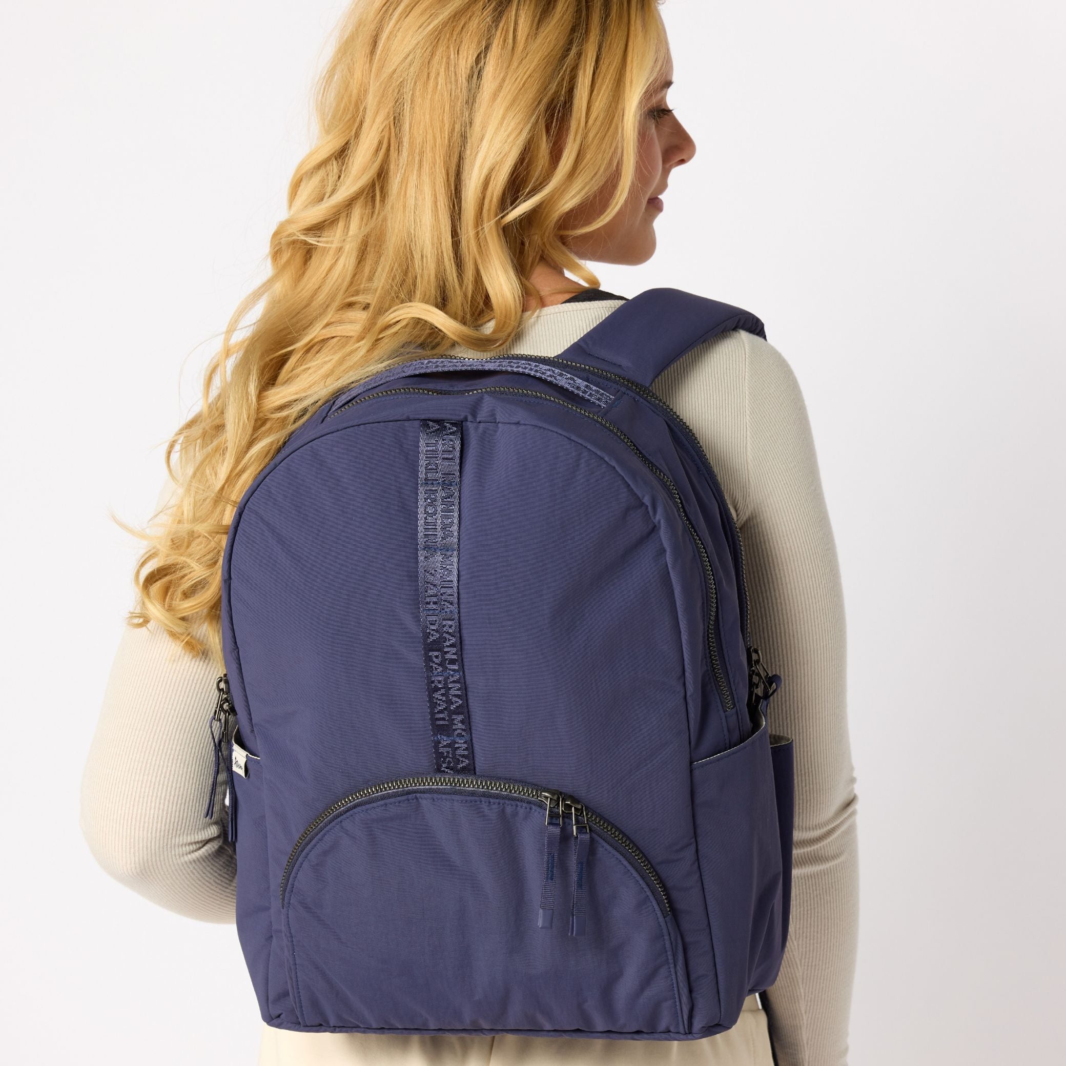Woman holding indigo travel backpack side view. #indigo