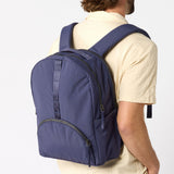 Man carrying purple travel daypack over shoulders. #indigo