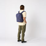 Man carrying navy travel daypack over one shoulder. #indigo