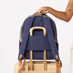 backview of the purple with brown tirm backpack on top of luggage using the sleeve #indigo_and_camel