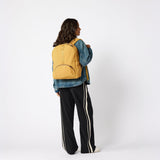Person carrying amber yellow travel backpack front view. #amber_yellow