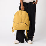 Person wearing amber travel daypack side view. #amber_yellow