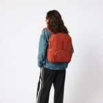 Woman wearing rust red travel carry-on backpack full length. #rust_red