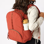 Woman with rust travel backpack water bottle in side pocket. #rust_red