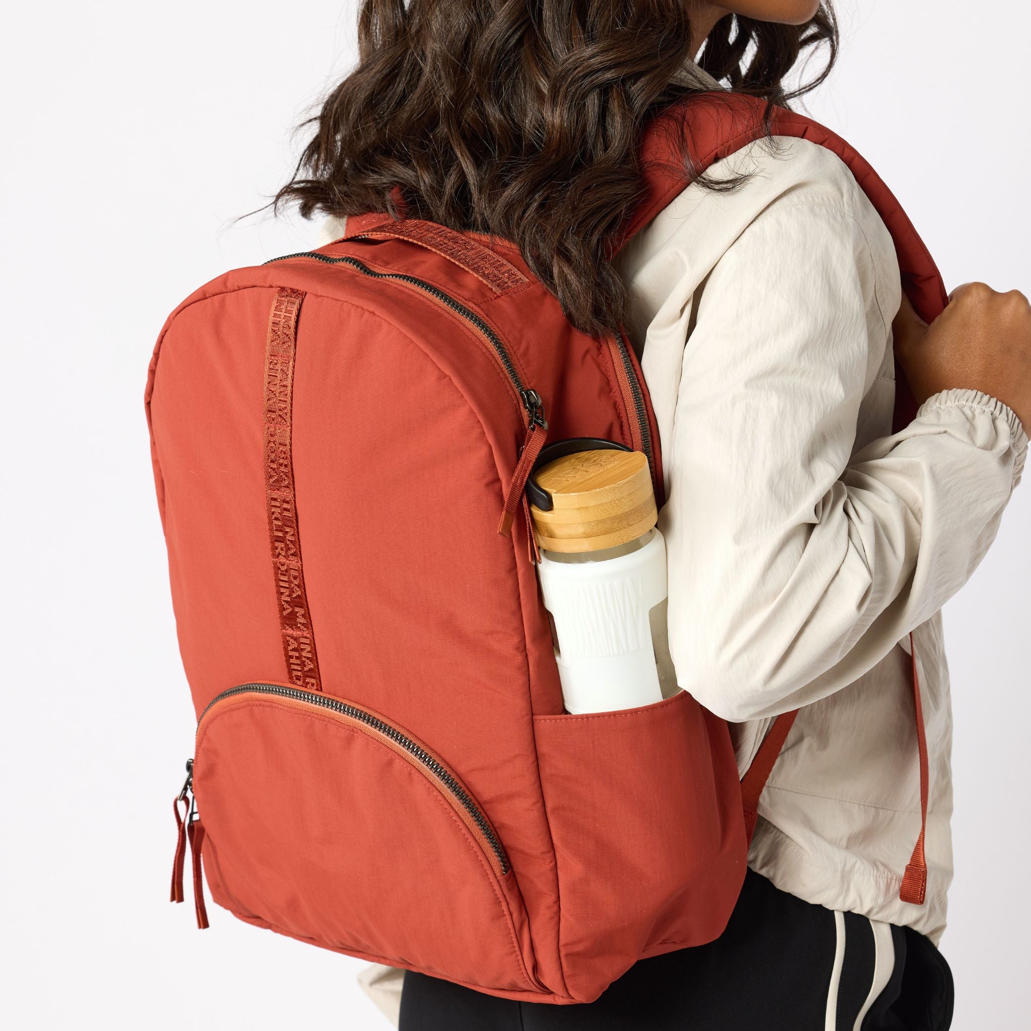 Woman with rust travel backpack water bottle in side pocket. #rust_red
