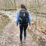 Person hiking on a trail with a backpack in a forest setting #black