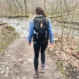 Person hiking on a trail with a backpack in a forest setting #black