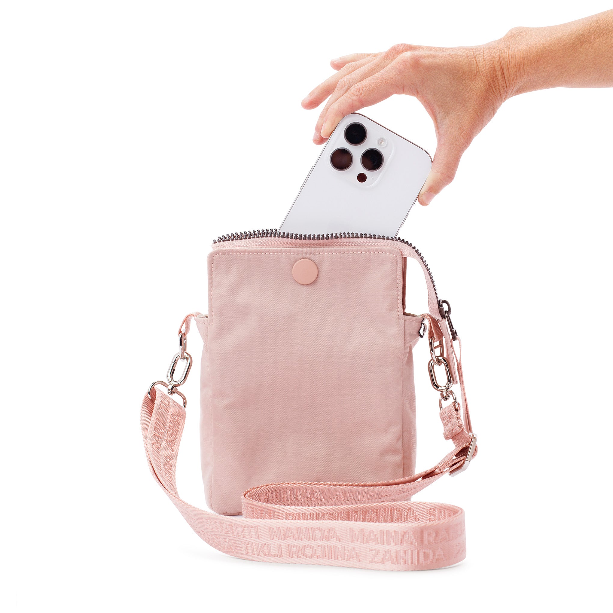 Pink crossbody bag with a hand holding a phone inside on a white background #blush